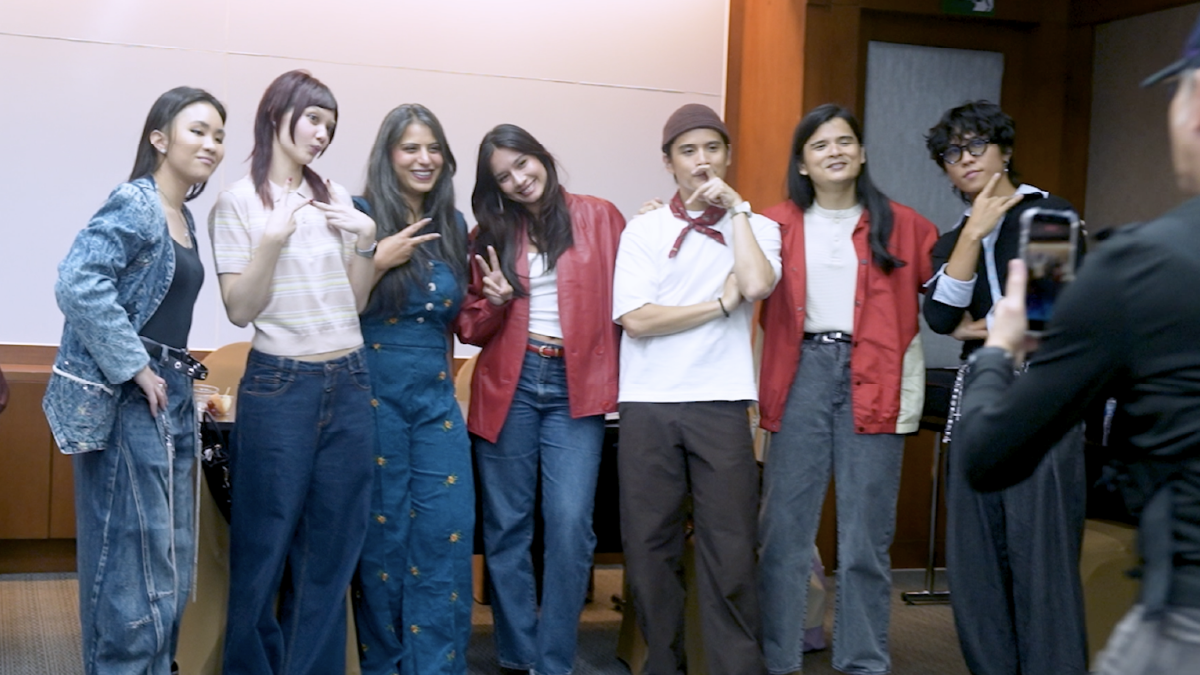 Behind the scenes: the artists posing together while a crew member films them on a phone